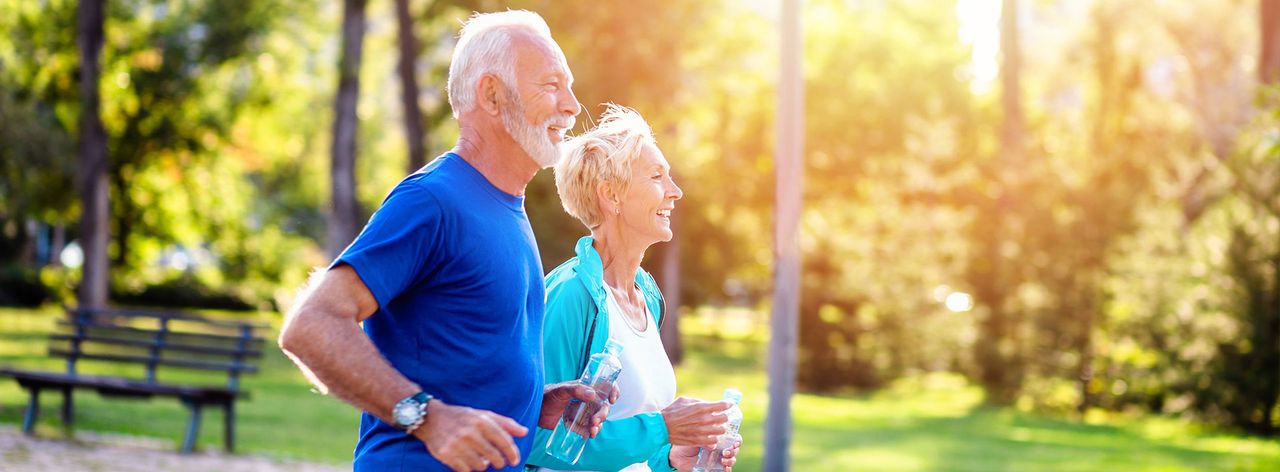 Older couple jogging together in a park